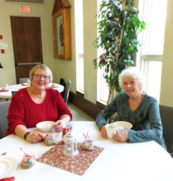 Minister Rev. Cathy Gradante sitting at a table beside Wendy Dunits