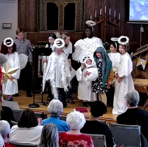 Children in white robes and halos acting out nativity scene at BUC
