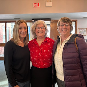 Three women with broad smiles gathered in the BUC narthex following the Gloria pageant in Dec 2024