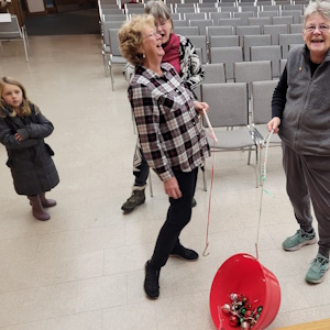 3 Adults & 1 child playing with a red bucket in Messy Church
